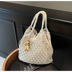 Detail of white woven cotton mesh tote bag with inner pouch and cartoon charm accessory