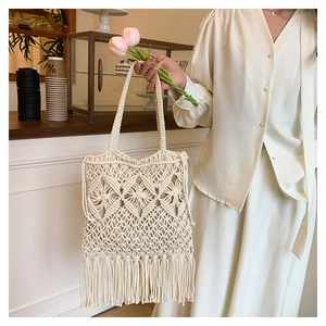 Detailed macro view of cream macrame tote bag with intricate weaving and long fringe tassels