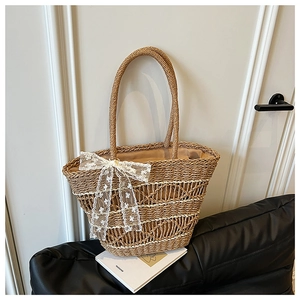 Detail of woven straw tote bag with a white lace bow and natural fiber texture