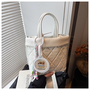 Detailed view of white quilted bucket bag with cute capybara pendant and braided rope