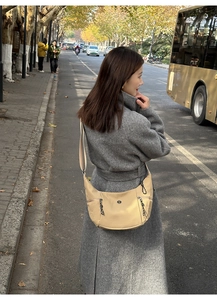 Détail du sac croissant beige clair avec bandoulière et tirettes de fermeture