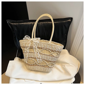Detail of woven straw tote bag featuring a decorative white lace bow and texture
