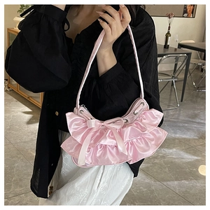Detail of pink satin handbag featuring layered ruffles and a decorative silk bow accent