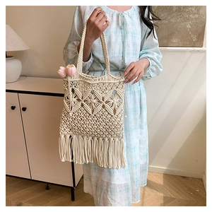 Detail of hand-woven off-white tote bag featuring geometric hollow patterns and long tassels