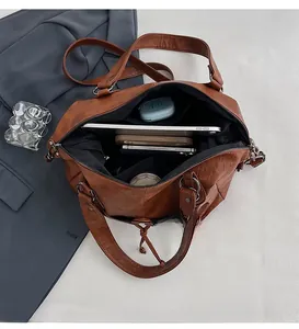 Internal view of brown leather bag showing large capacity with several tech accessories