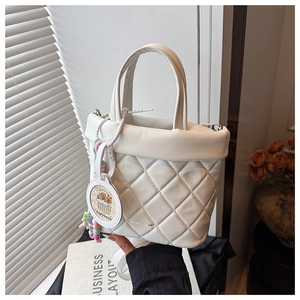 Detail of white quilted bucket bag featuring a diamond pattern and a cute capybara charm
