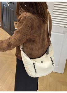 Détail du sac bandoulière demi-lune blanc cassé avec fermetures éclair décoratives