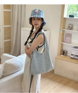 Detailed view of light blue checkered nylon tote bag and matching bucket hat on a sofa