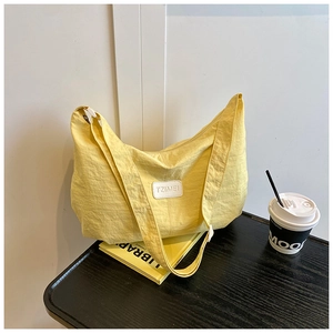 Detailed macro view of the light yellow nylon fabric texture and logo on the shoulder bag