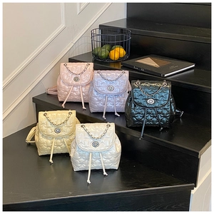 Close-up of mini quilted backpacks with star patterns and metal chain details on stairs