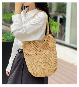 Detail shot of beige hollow woven tote bag with fringe charm and rope straps