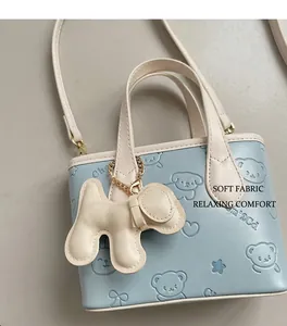 Détail du sac seau bleu clair avec motifs d'ours gaufrés et breloque chien mignonne