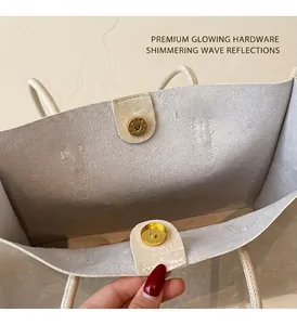 Detail of the golden magnetic buckle closure and textured cream faux leather tote bag