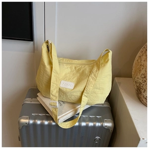 Detail of a bright yellow tote bag with textured nylon fabric and a white logo patch