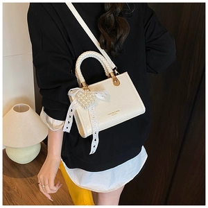 Detail of cream crossbody bag with textured faux leather and pearl lace bow accessory