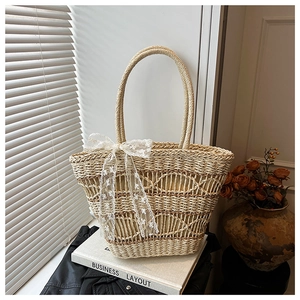 Detailed straw woven tote bag with white lace bow and intricate hollow-out texture