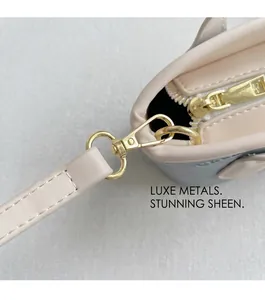 Gros plan sur les accessoires métalliques dorés et crochets du sac seau en cuir rose