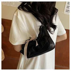 Detail of black pleated shoulder bag with pink ribbon bow detail in a stylish look