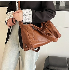 Close-up of vintage brown PU leather tote bag showing soft texture and metal hook detail