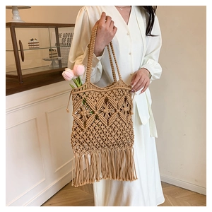 Detail of hand-woven straw tote bag with diamond patterns and fringe tassels