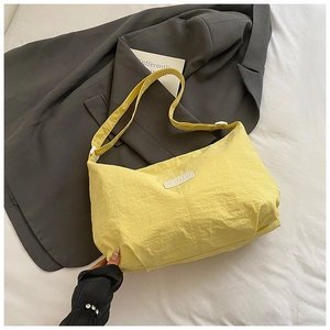 Detail view of yellow nylon dumpling bag with adjustable strap and textured fabric surface
