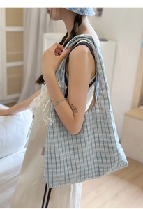 Detail of blue and white checkered nylon crescent bag with matching bucket hat on a model