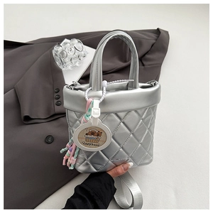 Detail of silver quilted bucket bag with wide strap and cute Capybara charm