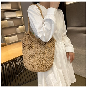 Détail du sac cabas en paille tissée ajourée avec poignée tressée et pompon décoratif