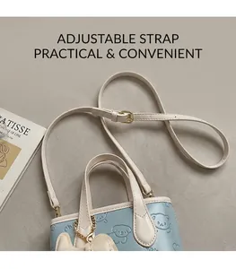 Détail de la bandoulière réglable en cuir crème et boucle dorée sur un sac seau bleu