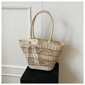 Detail of hand-woven straw tote bag featuring elegant white lace bow and round handles
