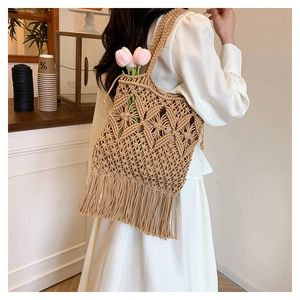 Detail of woven tote bag featuring complex geometric patterns and long tassels with tulips