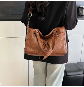 Detail of vintage brown tote bag showing supple faux leather texture and metal side ring