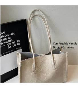 Close-up of cream PU leather tote bag showing soft pleated texture and slim shoulder straps