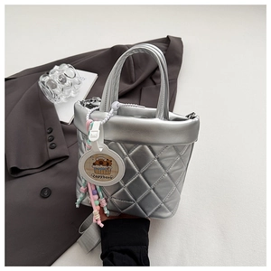Detail of silver quilted bucket bag with a cartoon capybara charm and beaded strap
