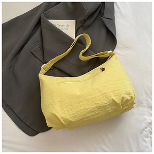 Detailed view of the yellow crossbody bag's crinkled nylon fabric and zipper pocket