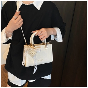 Close-up of white mini square bag with pearl heart charm and lace bow details