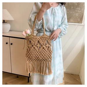 Detail of woven boho tote bag featuring long tassels and geometric hollow patterns
