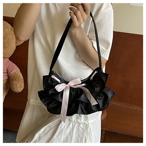 Close-up of black ruffled handbag featuring a prominent pink silk ribbon bow detail