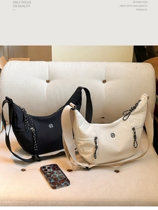 Détail de sacs bandoulière croissant en noir et beige sur canapé avec sangle réglable