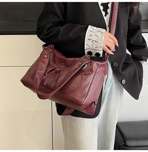 Detail of burgundy tote bag showing pebbled leather texture and metal ring hardware