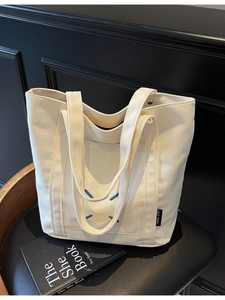 Minimalist off-white canvas tote bag with blue cross stitching for casual daily use