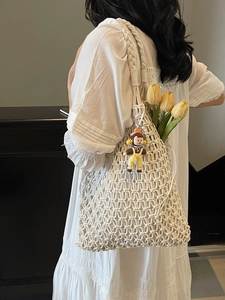 Chic hollow macramé woven tote bag in beige with a cute doll charm for beach or leisure