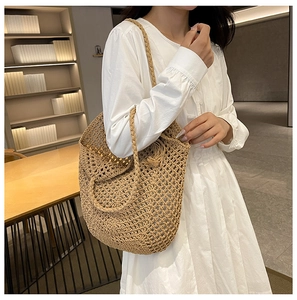 Gros plan détaillé du sac en paille tissé main avec motif ajouré et détail de pompon