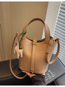 Chic khaki pebbled leather bucket bag with top handle, long strap and pony charm detail
