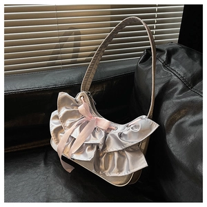 Detail of silver metallic hobo bag featuring ruffled pleats and a pink silk bow accent