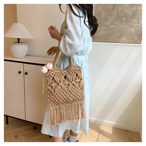 Detailed macro view of handcrafted woven texture and decorative tassels on a straw tote bag