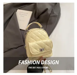 Detail view of the pale yellow quilted backpack featuring a silver twist lock and chain strap