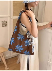 Detail of nylon dumpling bag with blue floral print and white lace bow decoration