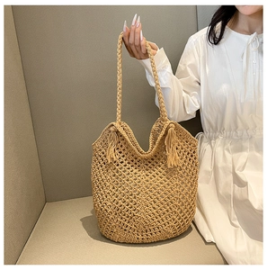 Détail macro du sac cabas en paille tissé à la main avec motif ajouré et pompons décoratifs