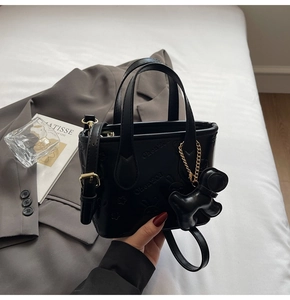 Détail du mini sac seau noir avec gaufrage lapin, breloque chien et bandoulière
